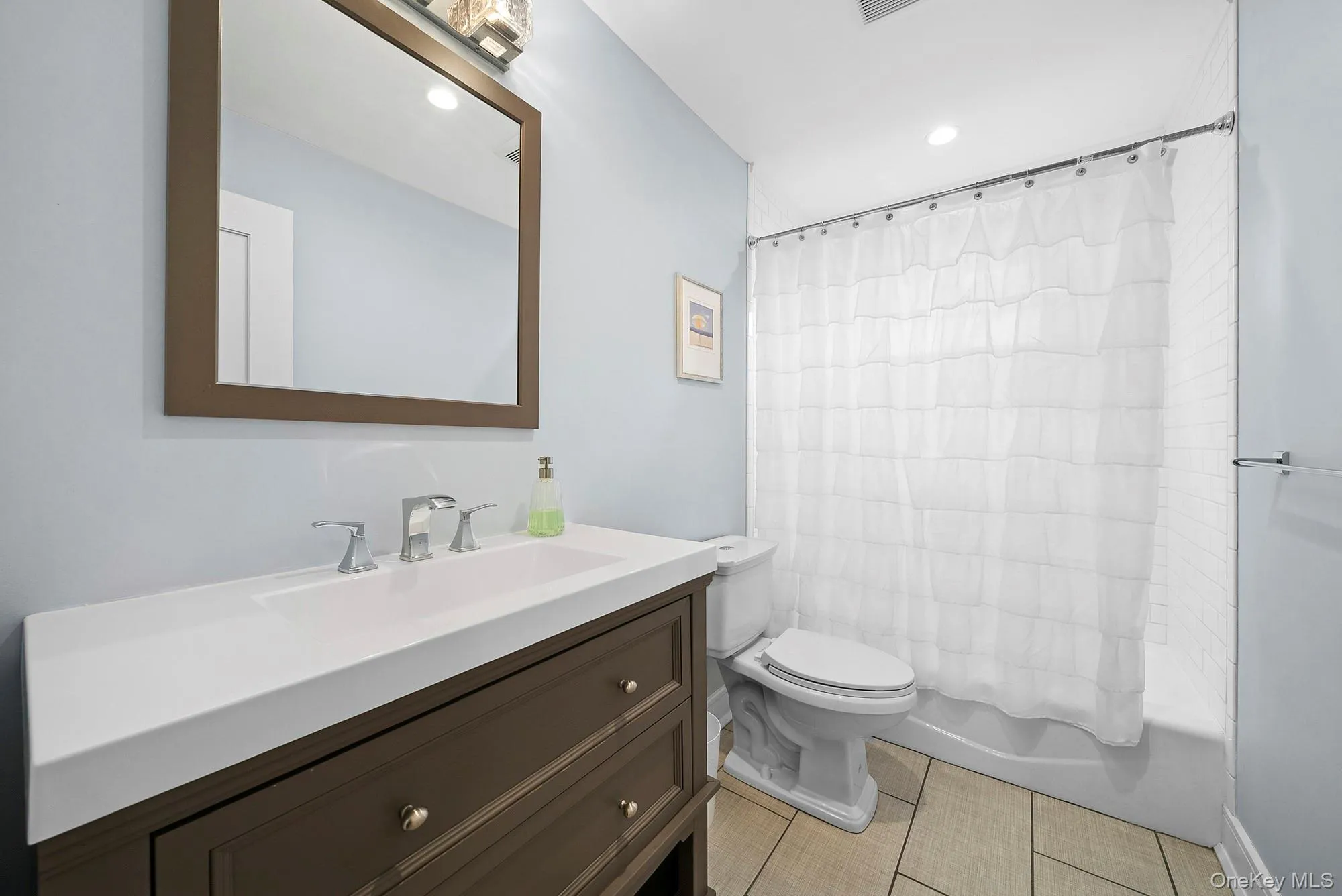 Full bathroom featuring vanity, shower / bath combo, light tile patterned floors, and recessed lighting Full bathroom featuring vanity, shower / bath combo, light tile patterned floors, and recessed lighting