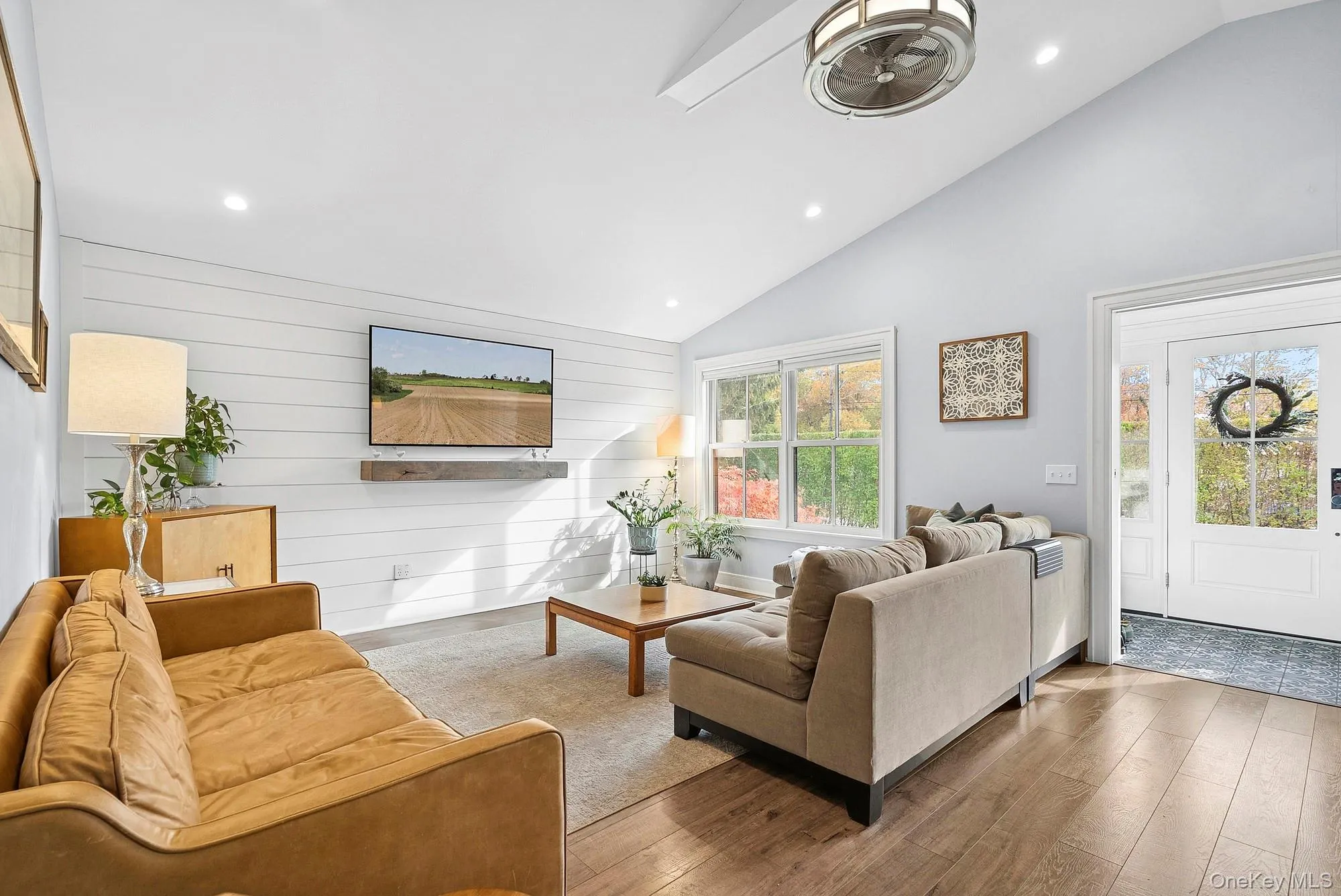Living area with wood walls, recessed lighting, wood-type flooring, and high vaulted ceiling Living area with wood walls, recessed lighting, wood-type flooring, and high vaulted ceiling