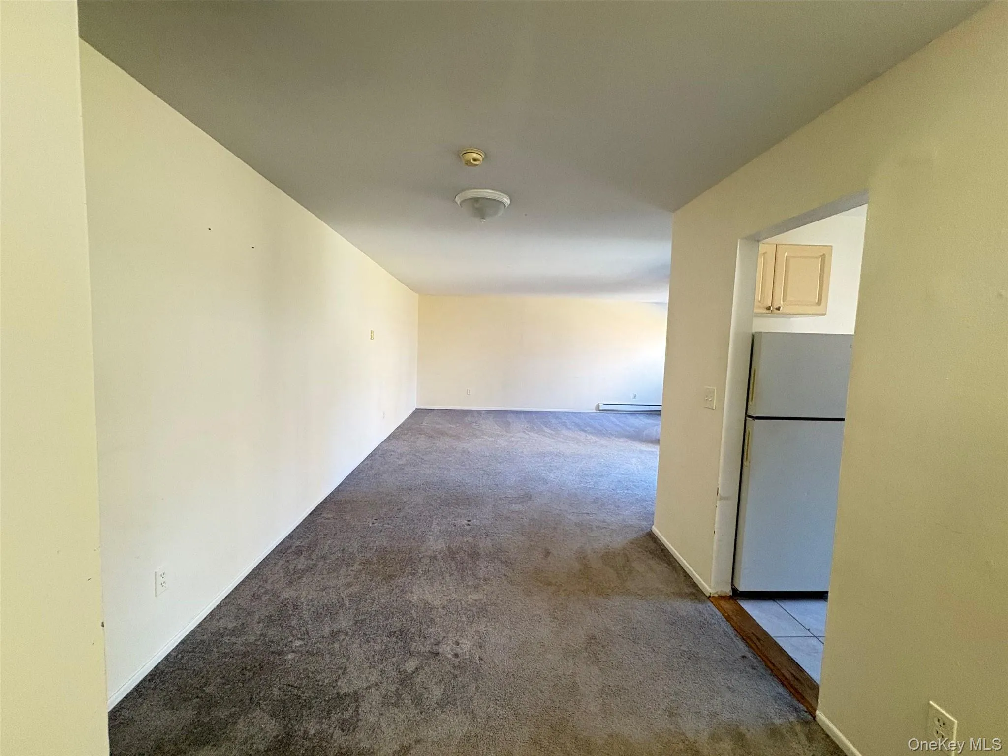 Corridor featuring dark colored carpet and baseboards Corridor featuring dark colored carpet and baseboards