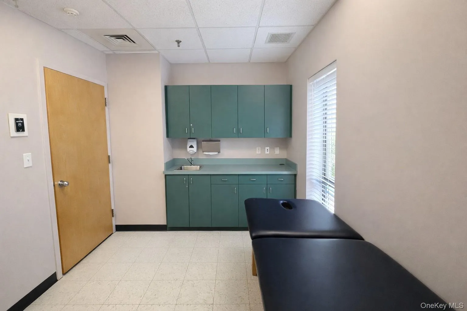 Kitchen featuring green cabinetry, a paneled ceiling, and light countertops Kitchen featuring green cabinetry, a paneled ceiling, and light countertops