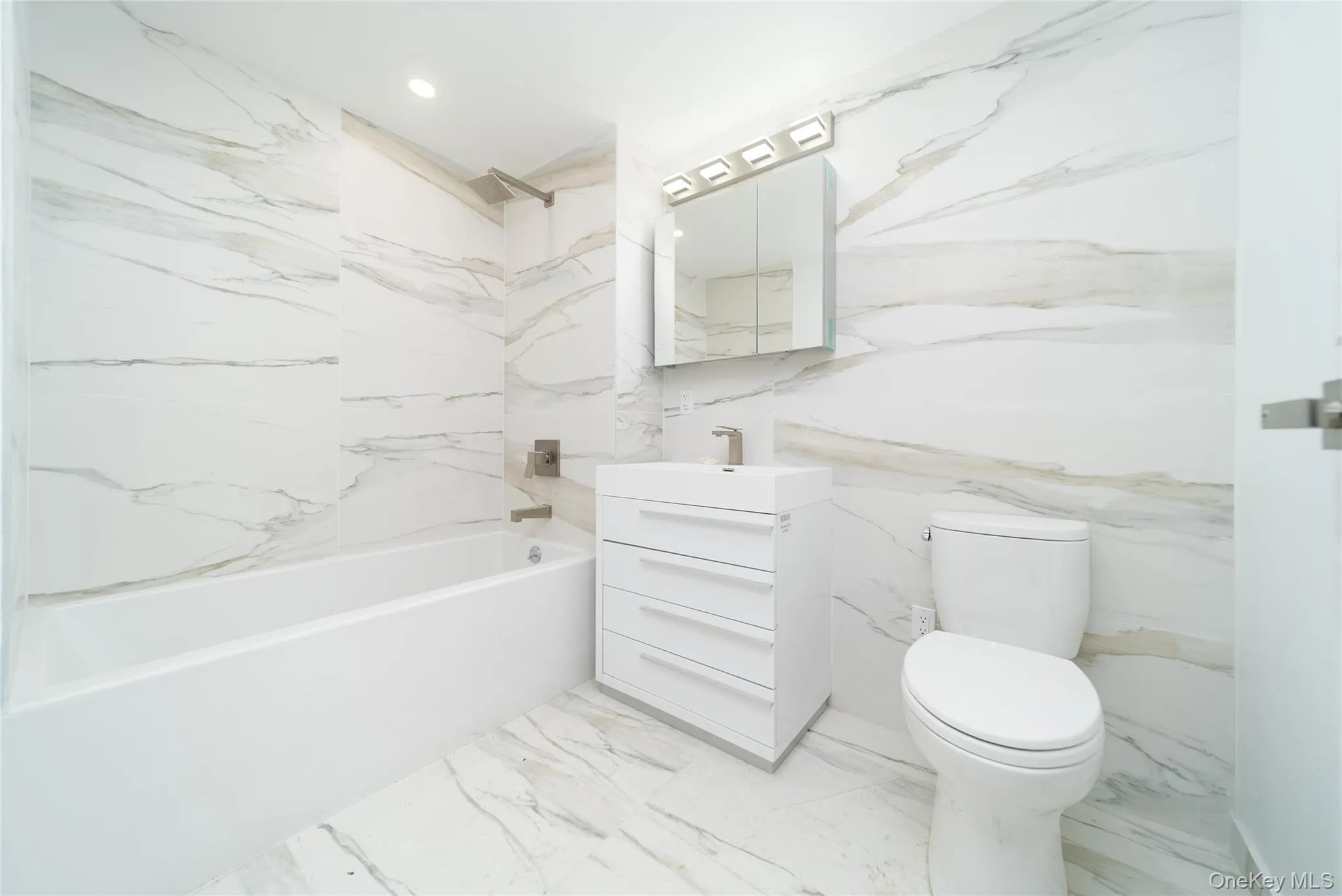 Bathroom featuring stone wall, a combined bath / shower with marble appearance, vanity, recessed lighting, and light marble finish flooring Bathroom featuring stone wall, a combined bath / shower with marble appearance, vanity, recessed lighting, and light marble finish flooring