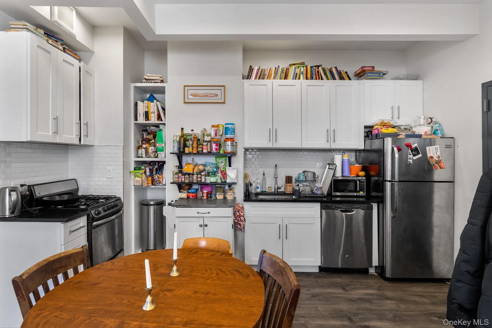 Kitchen featuring open shelves, appliances with stainless steel finishes, and white cabinetry Kitchen featuring open shelves, appliances with stainless steel finishes, and white cabinetry