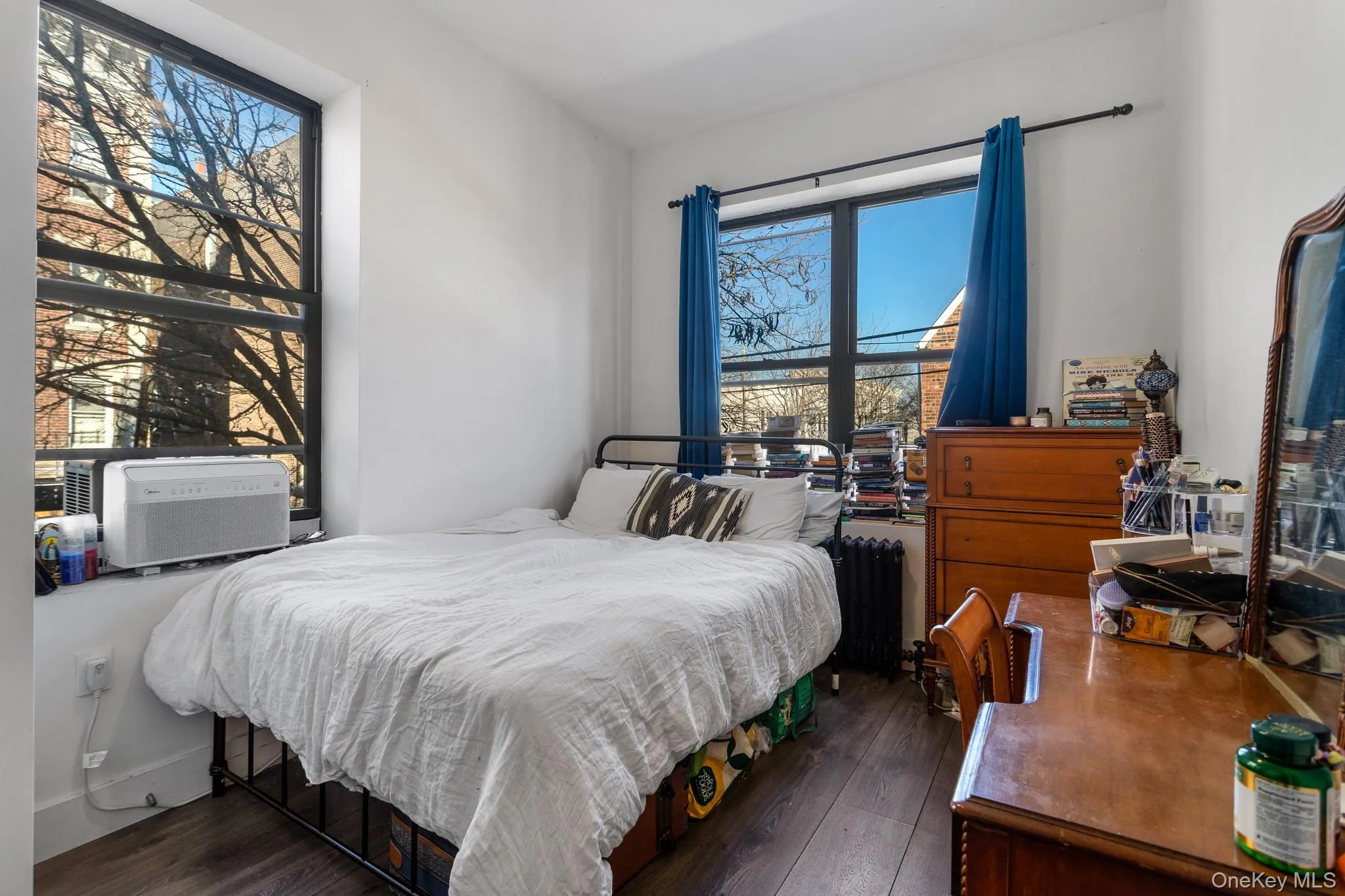 Bedroom featuring dark wood finished floors, radiator, and cooling unit Bedroom featuring dark wood finished floors, radiator, and cooling unit