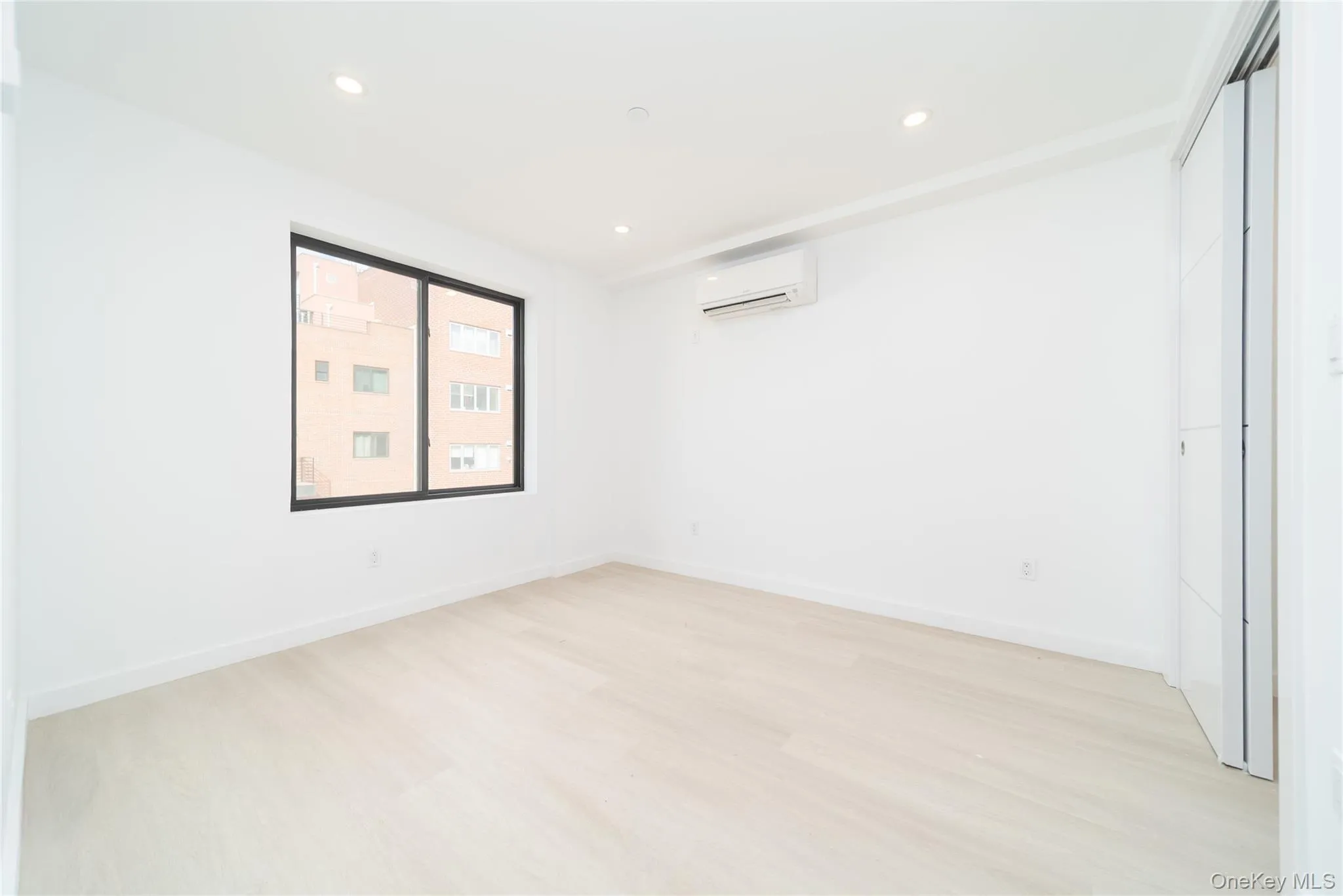 Spare room with light wood-type flooring, a wall unit AC, and recessed lighting Spare room with light wood-type flooring, a wall unit AC, and recessed lighting