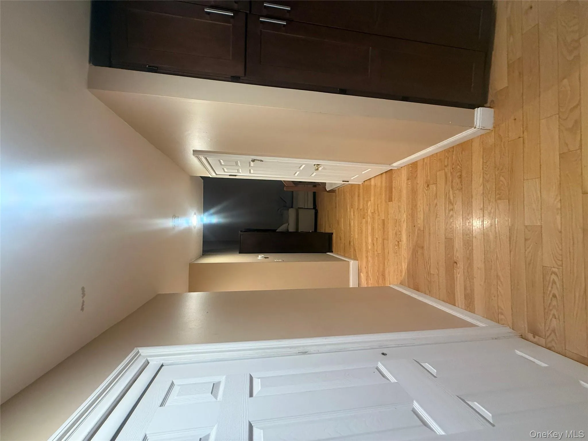 Hallway featuring hardwood floors, classic six-panel doors, and built-in dark wood cabinetry for extra storage. Hallway featuring hardwood floors, classic six-panel doors, and built-in dark wood cabinetry for extra storage.