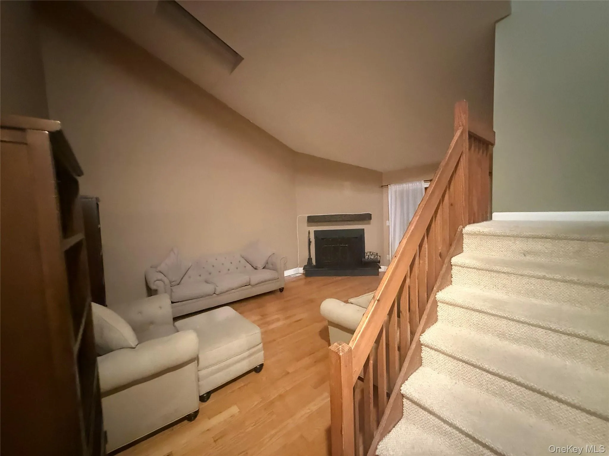 Living area with light wood-style floors, lofted ceiling, and a fireplace with raised hearth Living area with light wood-style floors, lofted ceiling, and a fireplace with raised hearth