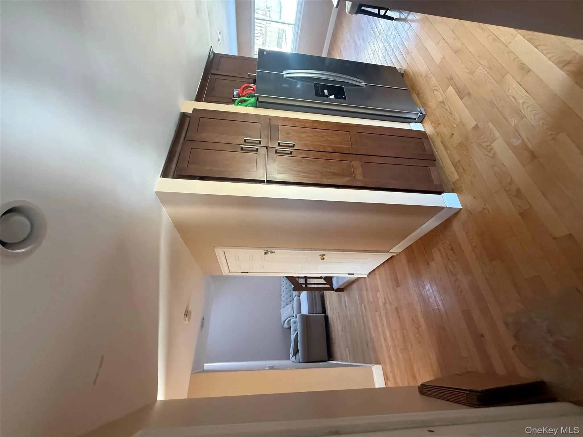 Functional transition area with warm hardwood flooring, built-in pantry storage, and a stainless steel refrigerator, leading to the open living spaces. Functional transition area with warm hardwood flooring, built-in pantry storage, and a stainless steel refrigerator, leading to the open living spaces.