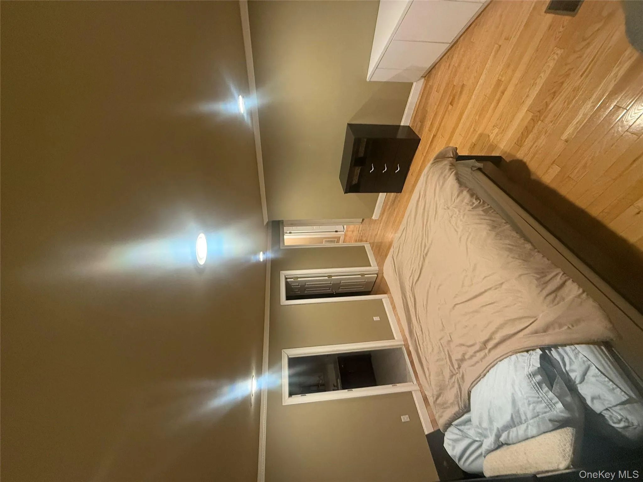 Spacious primary bedroom featuring warm hardwood flooring, recessed lighting, and elegant crown molding. Spacious primary bedroom featuring warm hardwood flooring, recessed lighting, and elegant crown molding.