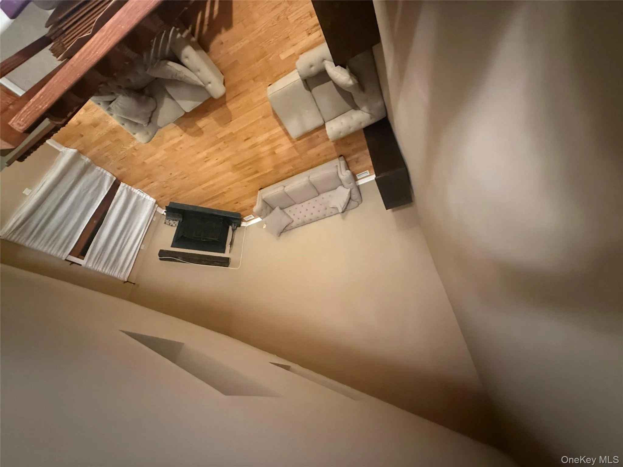 Expansive living room with vaulted ceilings, hardwood flooring, and a cozy fireplace, viewed from the upper-level loft. Expansive living room with vaulted ceilings, hardwood flooring, and a cozy fireplace, viewed from the upper-level loft.