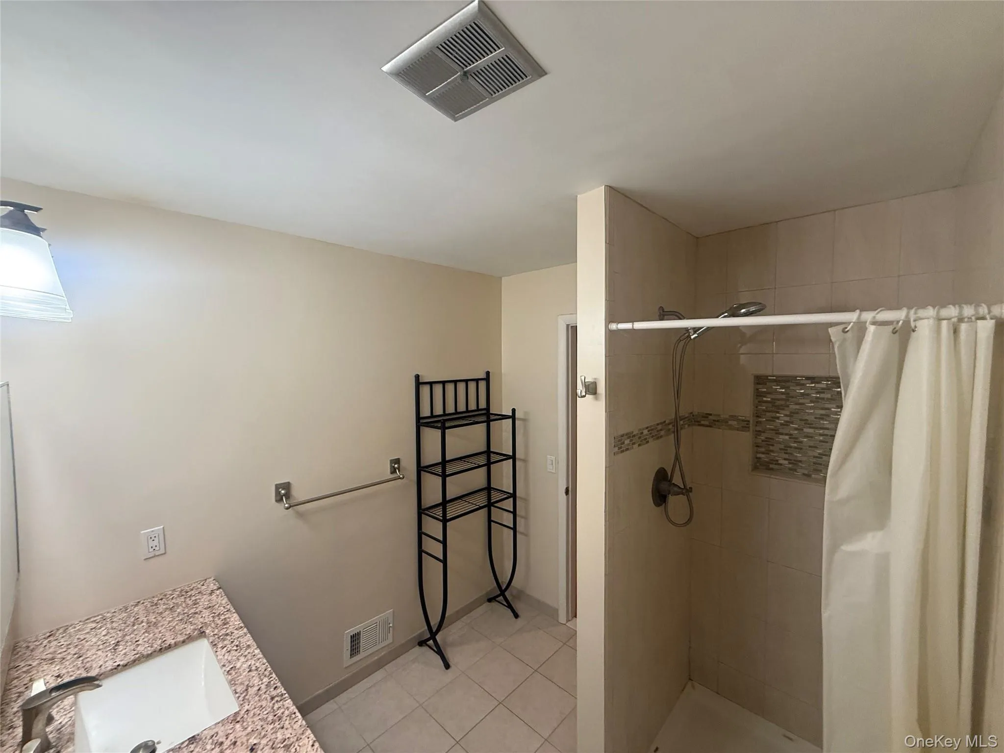 Full bath with vanity, a shower stall, and light tile patterned floors Full bath with vanity, a shower stall, and light tile patterned floors
