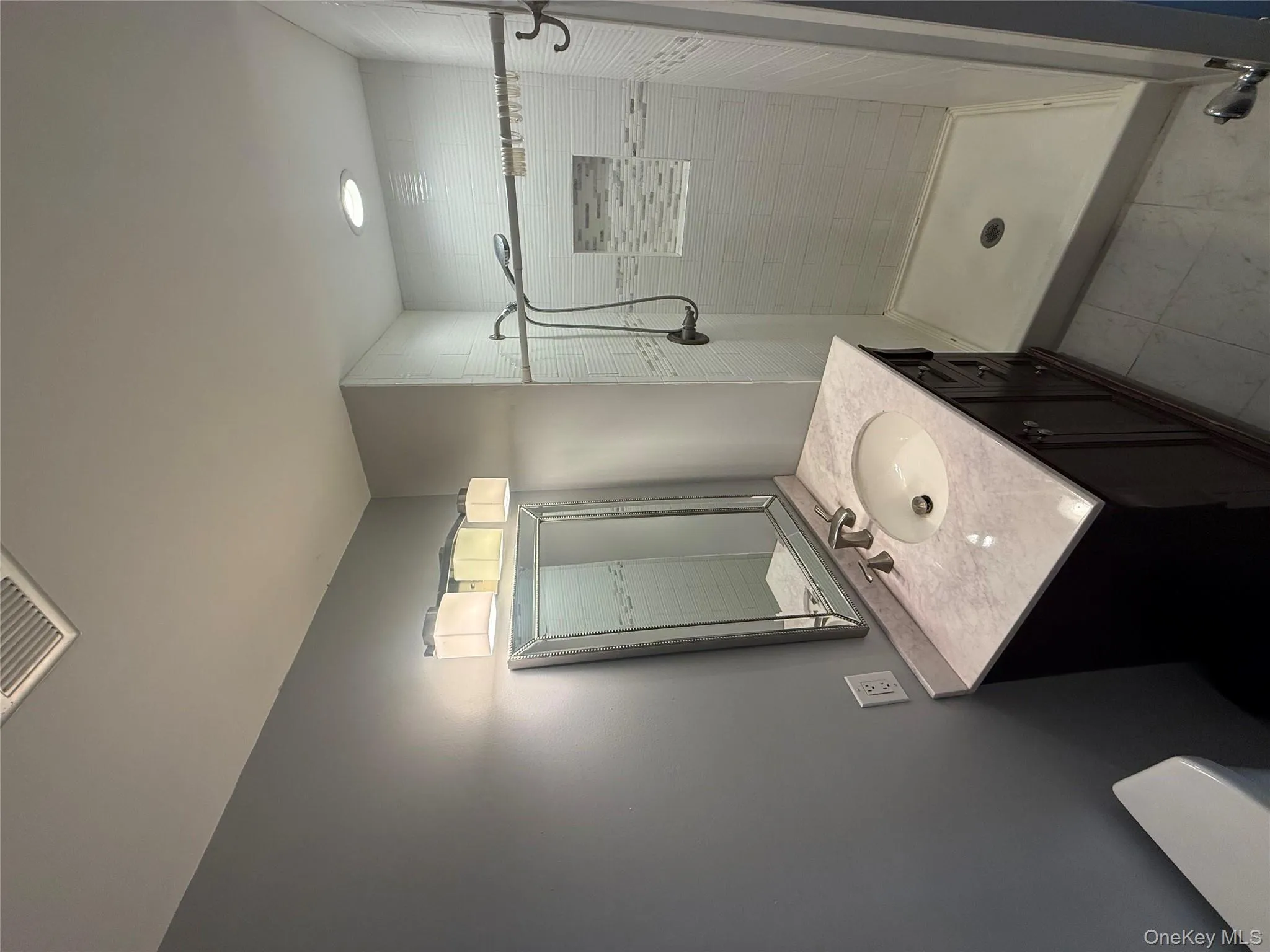 Modern bathroom featuring a marble-top vanity, updated lighting, and a glass-mirrored medicine cabinet alongside a tiled walk-in shower. Modern bathroom featuring a marble-top vanity, updated lighting, and a glass-mirrored medicine cabinet alongside a tiled walk-in shower.