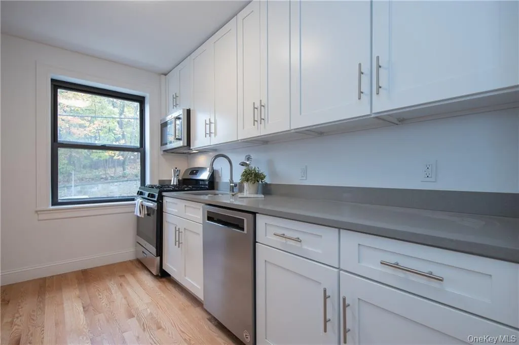 Kitchen with sink, white cabinets, light wood-type flooring, and appliances with stainless steel finishes Kitchen with sink, white cabinets, light wood-type flooring, and appliances with stainless steel finishes