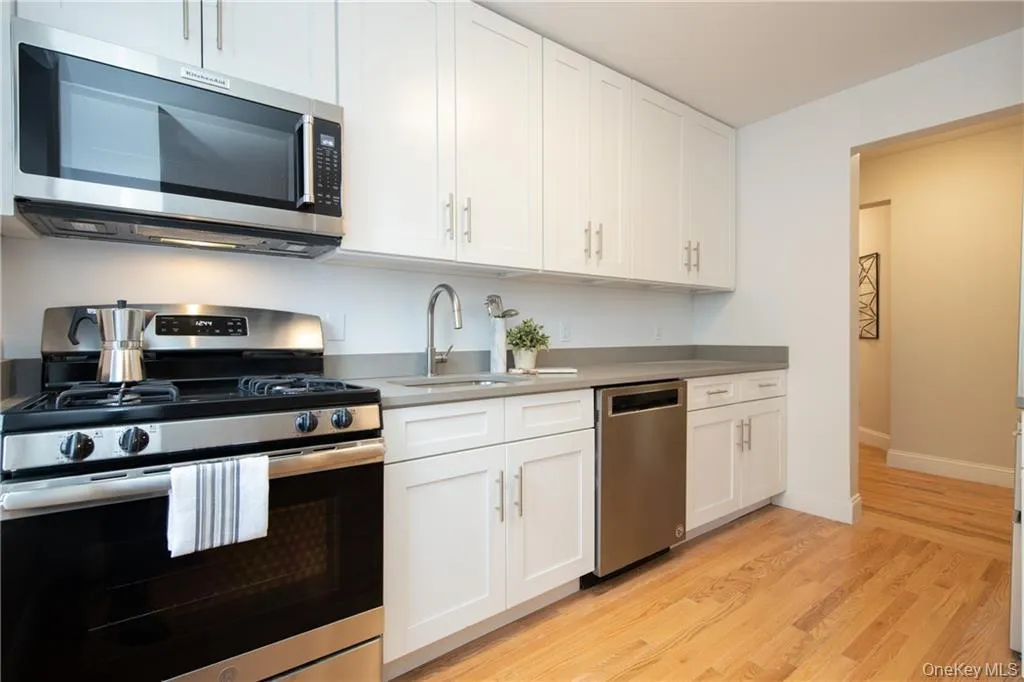 Kitchen with white cabinets, appliances with stainless steel finishes, light hardwood / wood-style floors, and sink Kitchen with white cabinets, appliances with stainless steel finishes, light hardwood / wood-style floors, and sink