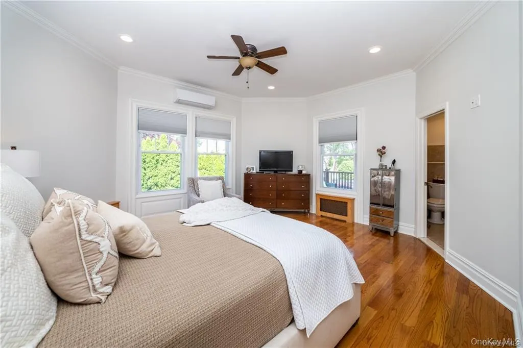 Bedroom with ornamental molding, wood finished floors, a wall mounted air conditioner, a ceiling fan, and recessed lighting Bedroom with ornamental molding, wood finished floors, a wall mounted air conditioner, a ceiling fan, and recessed lighting