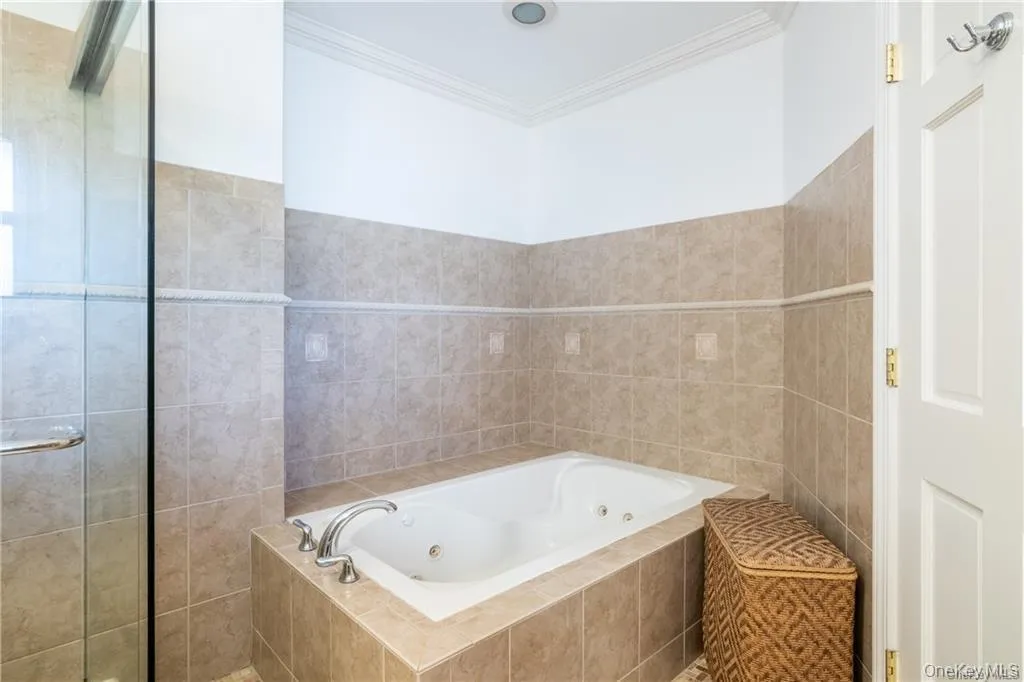 Full bath with a whirlpool tub, tile walls, and crown molding Full bath with a whirlpool tub, tile walls, and crown molding
