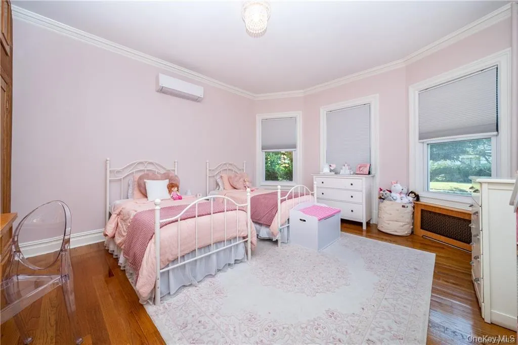 Bedroom featuring radiator, crown molding, an AC wall unit, and hardwood / wood-style flooring Bedroom featuring radiator, crown molding, an AC wall unit, and hardwood / wood-style flooring