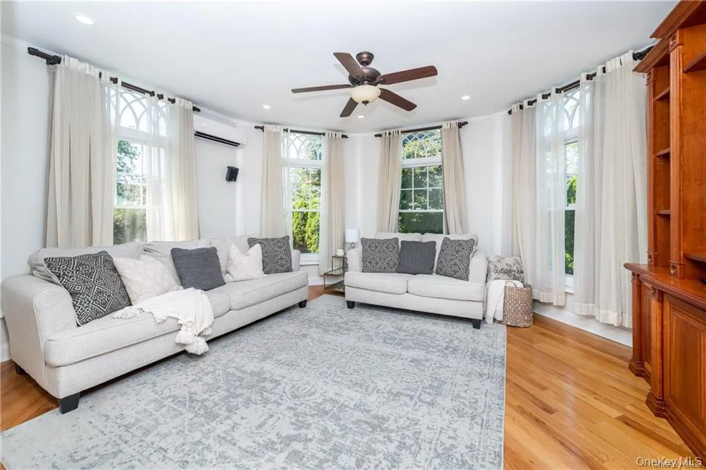 Living room featuring light wood-style floors, a ceiling fan, a wall unit AC, and recessed lighting Living room featuring light wood-style floors, a ceiling fan, a wall unit AC, and recessed lighting