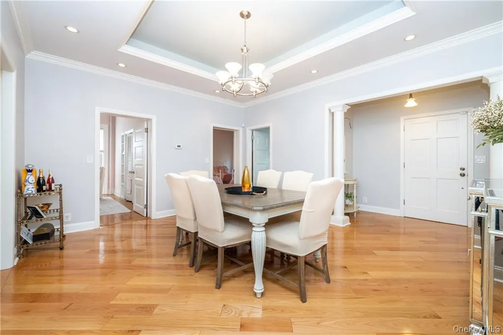 Dining room featuring a tray ceiling, recessed lighting, crown molding, light wood-type flooring, and a chandelier Dining room featuring a tray ceiling, recessed lighting, crown molding, light wood-type flooring, and a chandelier