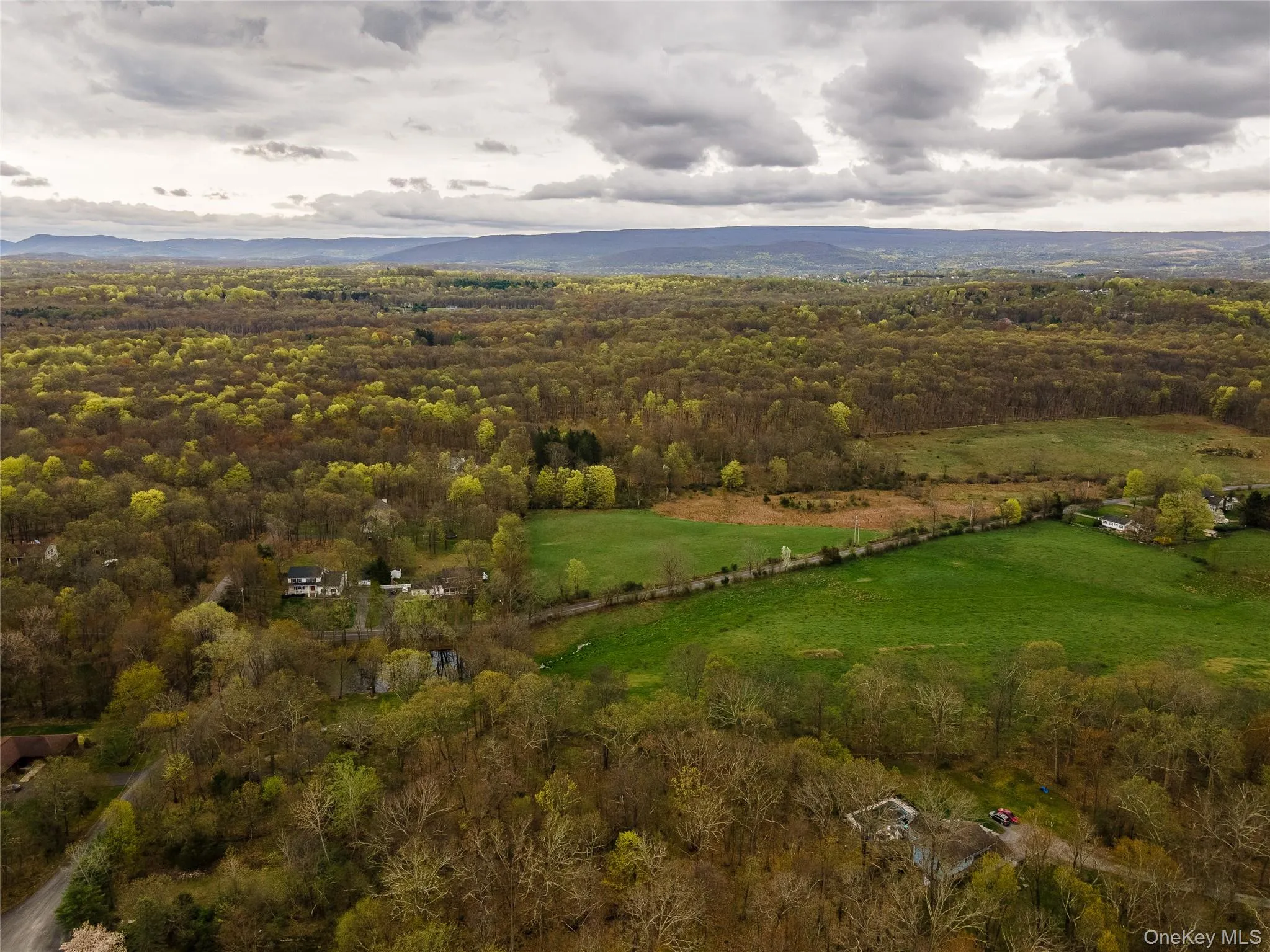 Aerial view of property's location featuring a heavily wooded area and a mountainous background Aerial view of property's location featuring a heavily wooded area and a mountainous background