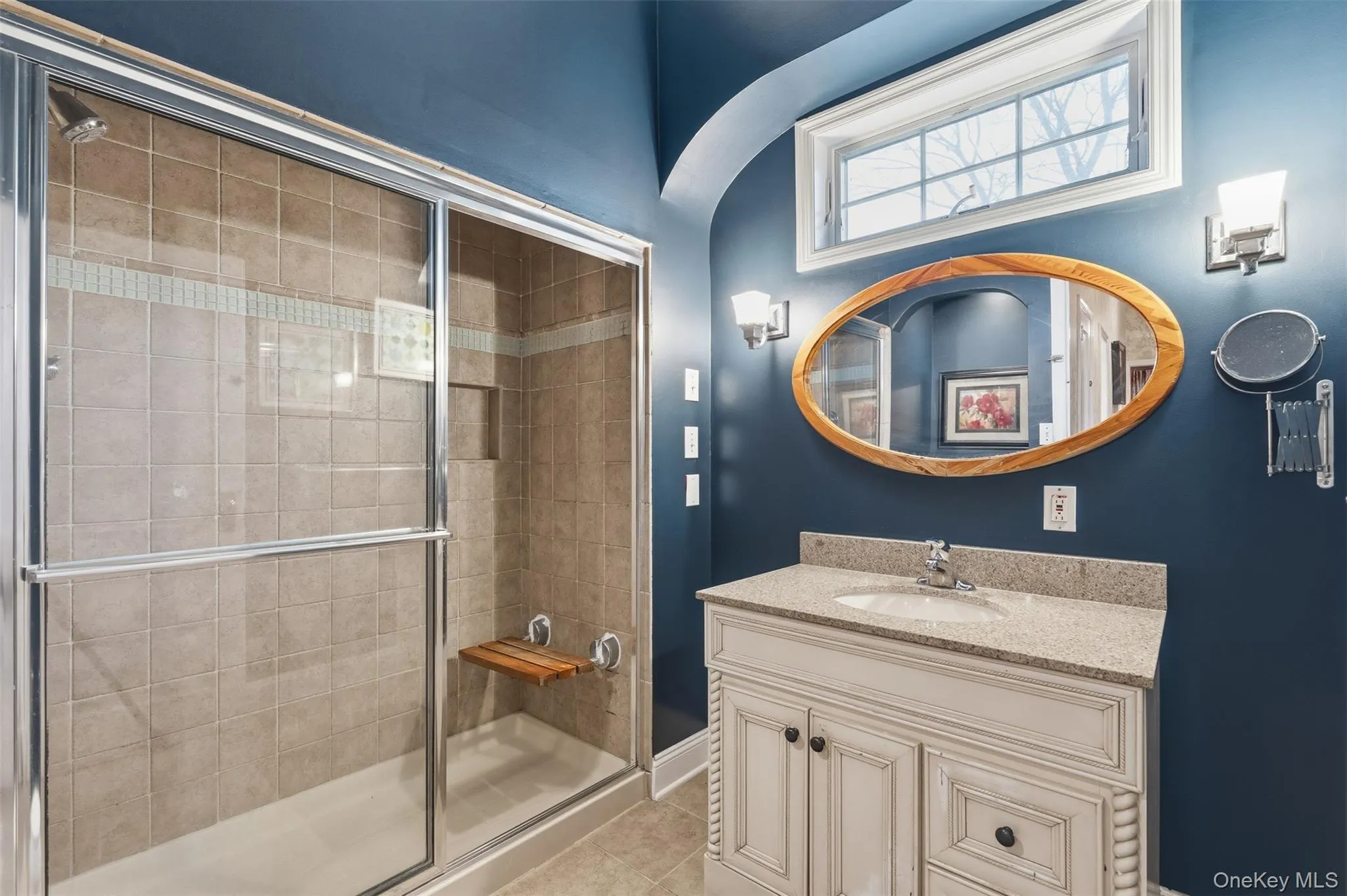 Full bath with vanity, a shower stall, and light tile patterned floors Full bath with vanity, a shower stall, and light tile patterned floors