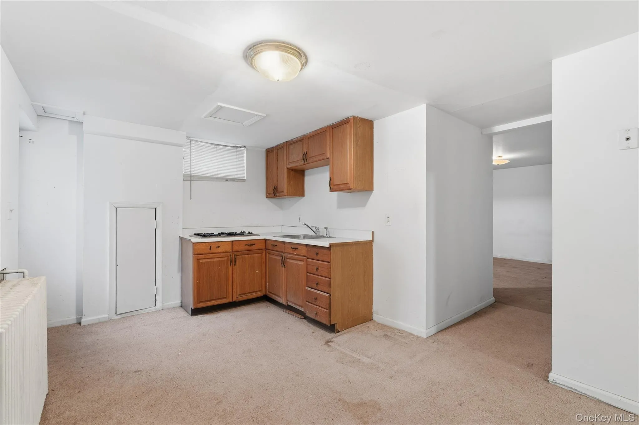 Kitchen with light countertops, brown cabinets, and light colored carpet Kitchen with light countertops, brown cabinets, and light colored carpet