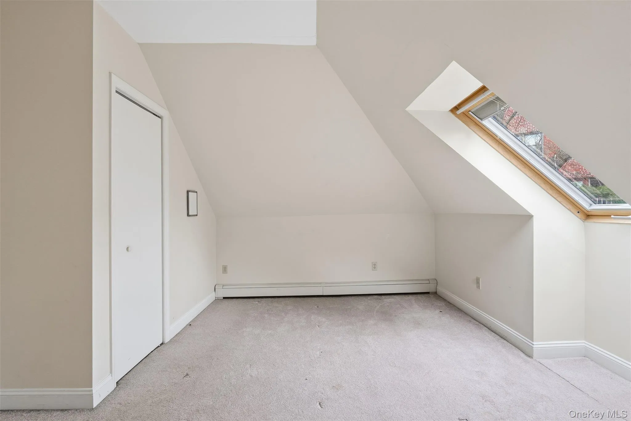 Bonus room featuring a skylight, vaulted ceiling, a baseboard heating unit, and light carpet Bonus room featuring a skylight, vaulted ceiling, a baseboard heating unit, and light carpet