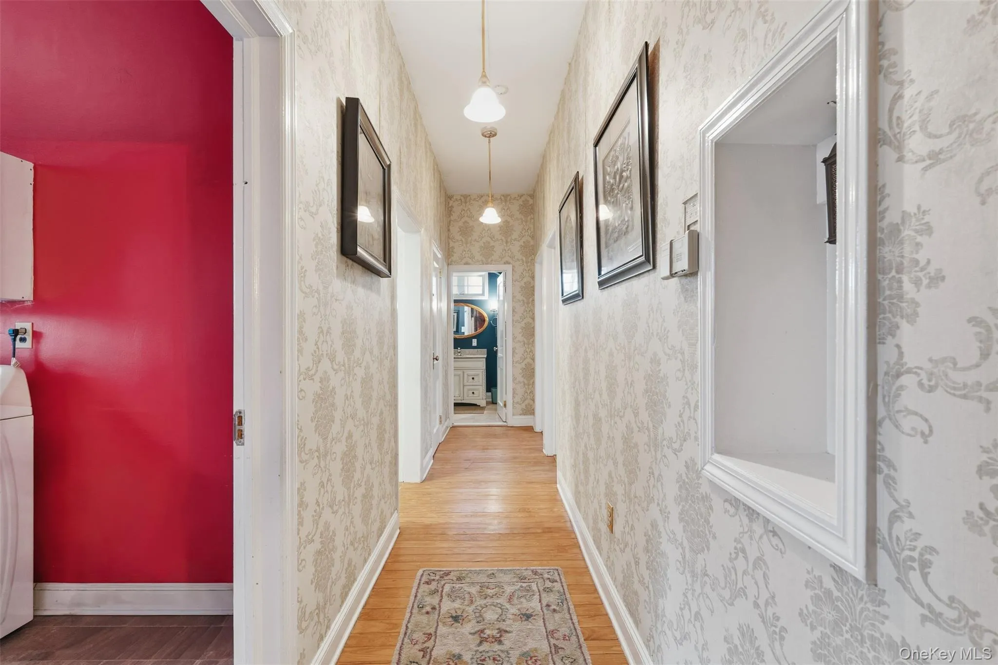 Hall featuring light wood-style flooring, washer / clothes dryer, and wallpapered walls Hall featuring light wood-style flooring, washer / clothes dryer, and wallpapered walls