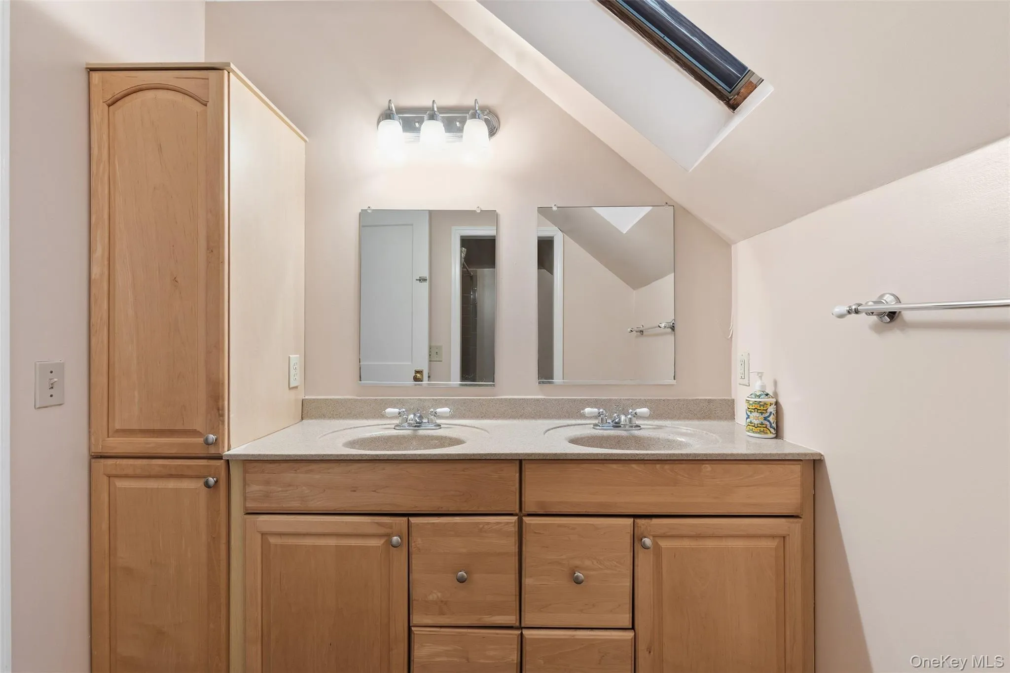 Bathroom featuring double vanity, a skylight, and lofted ceiling Bathroom featuring double vanity, a skylight, and lofted ceiling