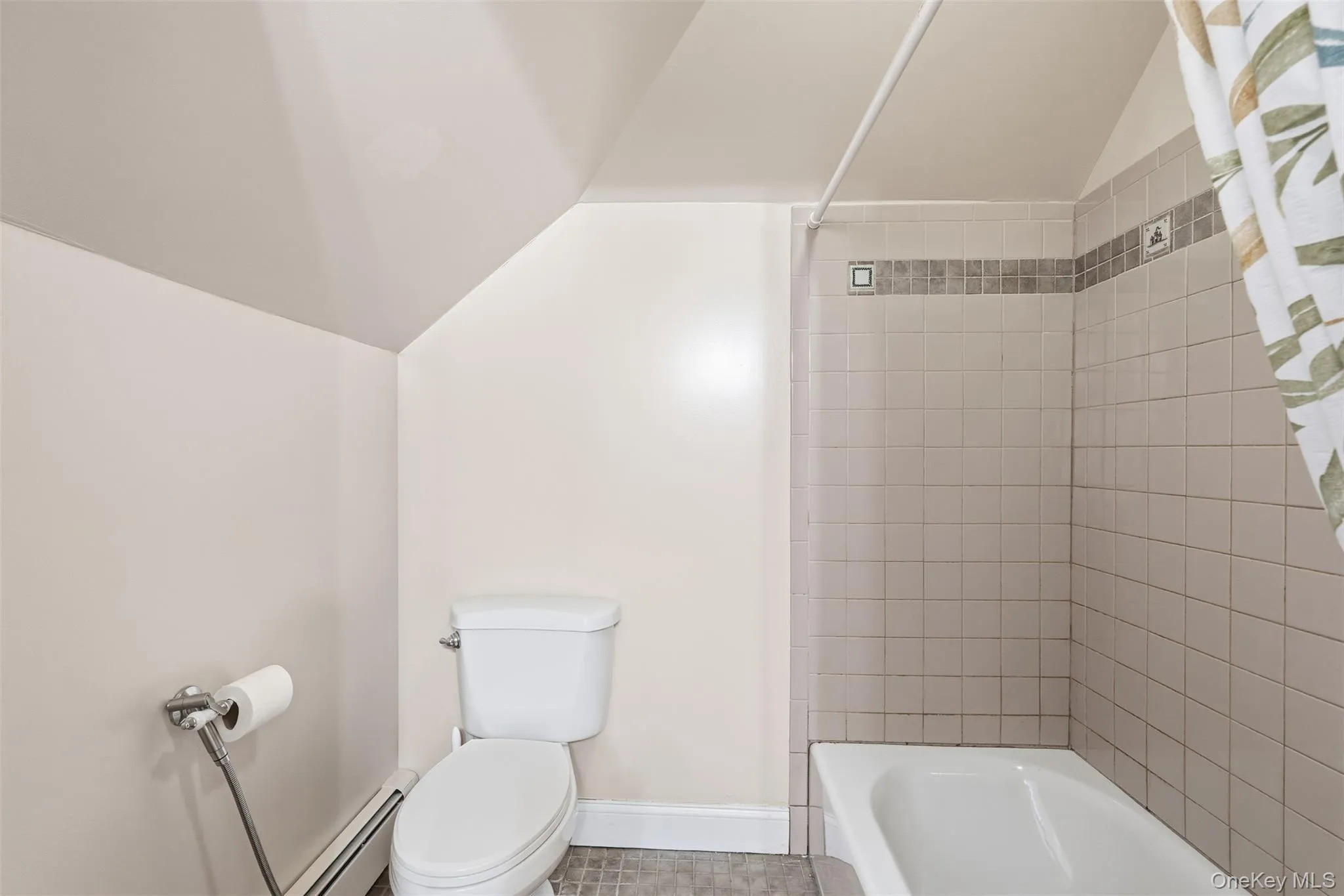 Bathroom with lofted ceiling, bathtub / shower combination, a baseboard radiator, and tile patterned flooring Bathroom with lofted ceiling, bathtub / shower combination, a baseboard radiator, and tile patterned flooring