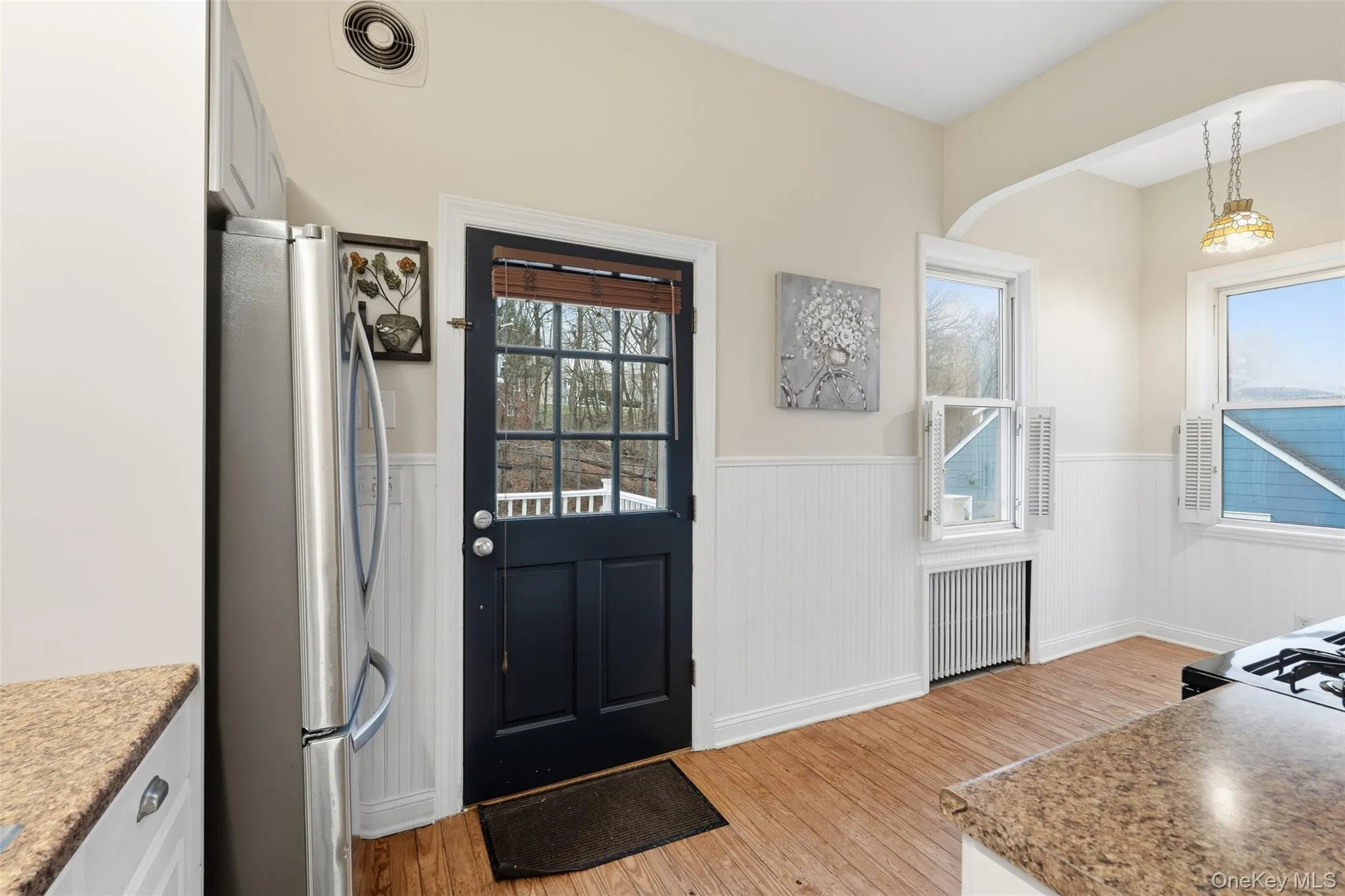 Foyer with radiator, wainscoting, and light wood finished floors Foyer with radiator, wainscoting, and light wood finished floors