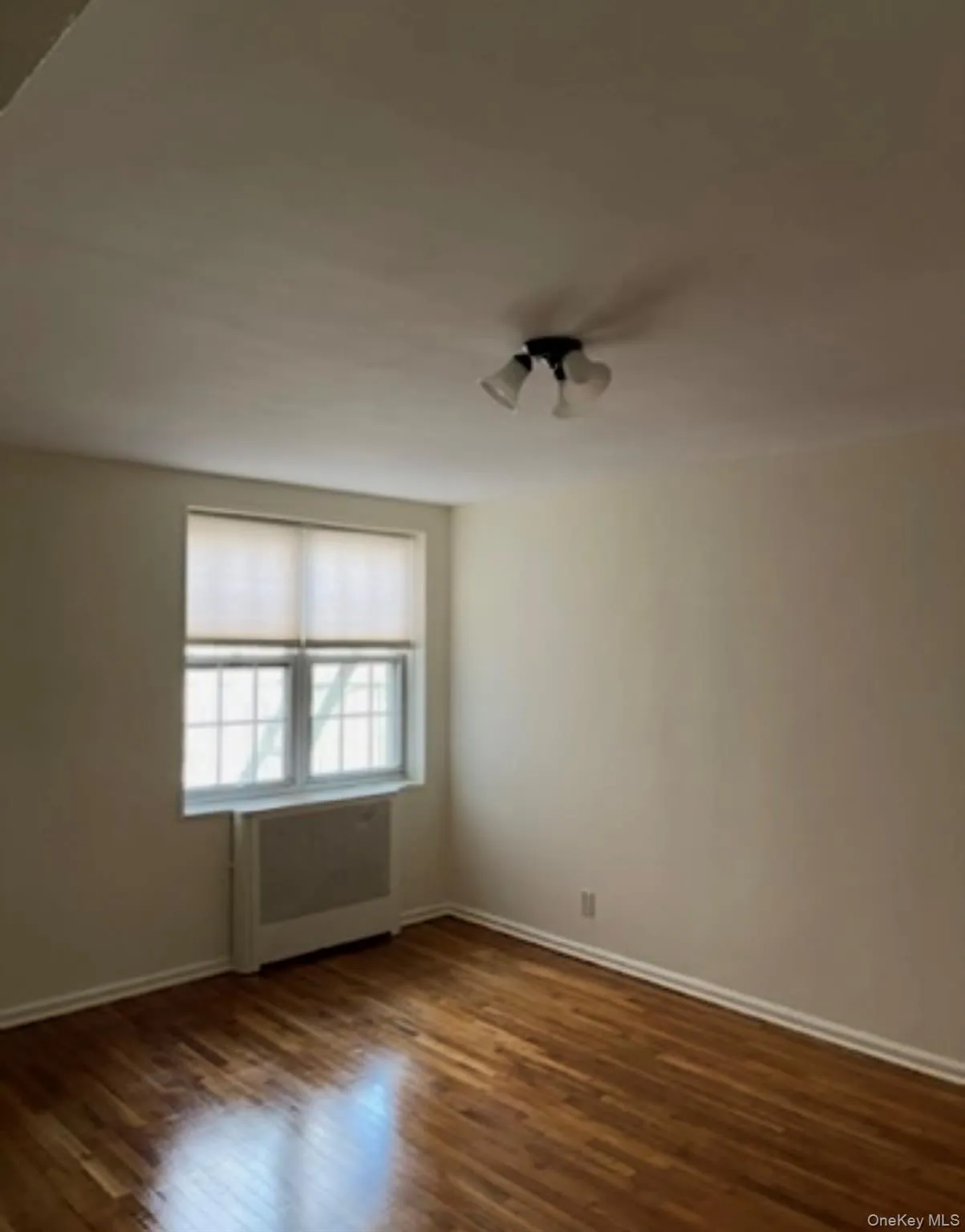 Empty room with dark wood-style flooring and baseboards Empty room with dark wood-style flooring and baseboards