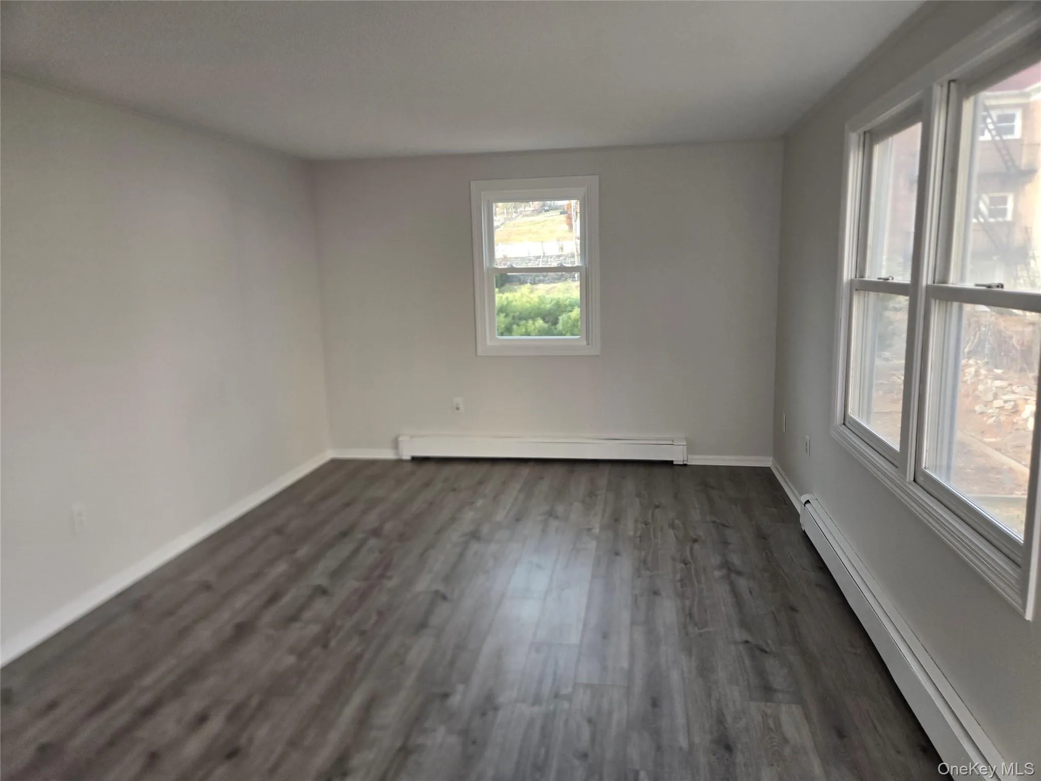 Spare room featuring a baseboard heating unit, a baseboard radiator, and dark wood-type flooring Spare room featuring a baseboard heating unit, a baseboard radiator, and dark wood-type flooring