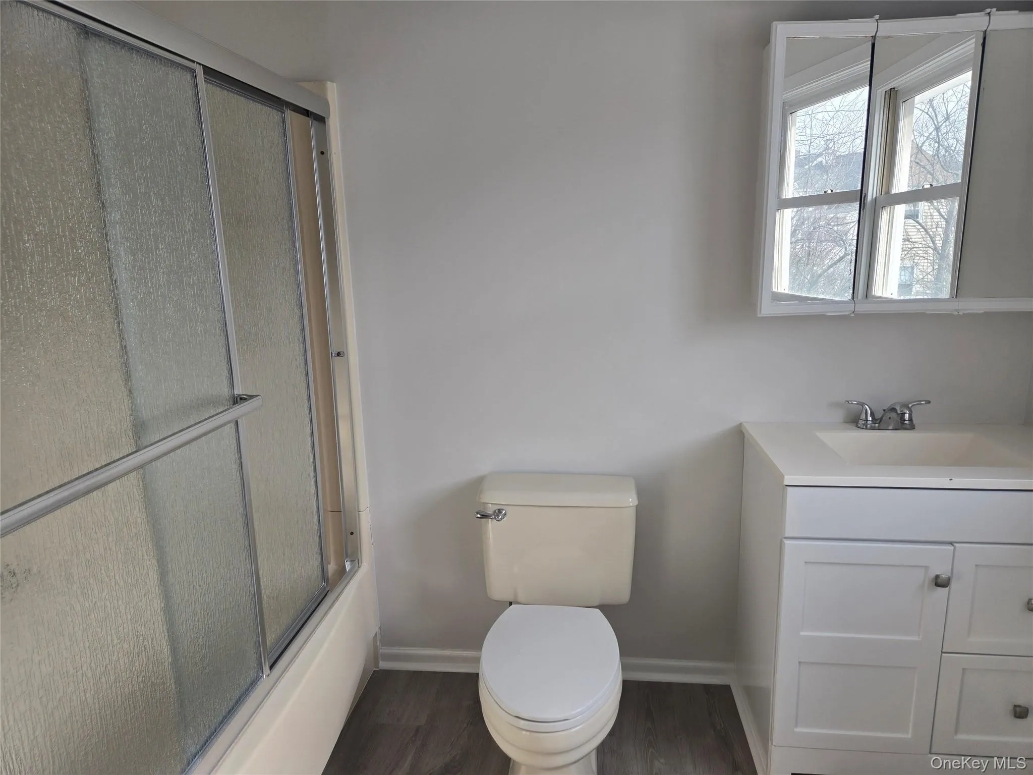 Bathroom with vanity, dark wood finished floors, and enclosed tub / shower combo Bathroom with vanity, dark wood finished floors, and enclosed tub / shower combo