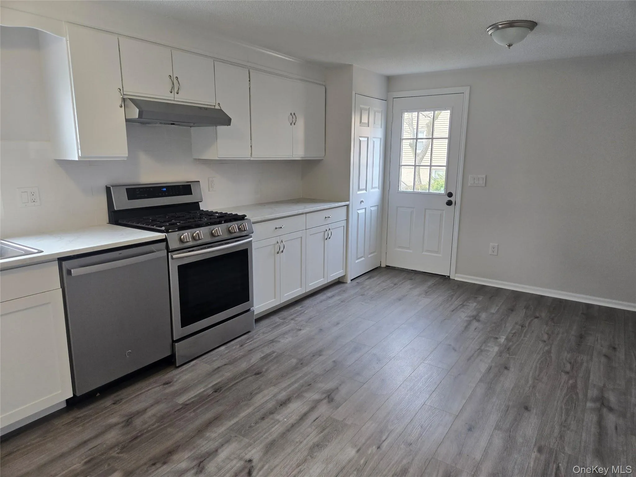 Kitchen with white cabinetry, appliances with stainless steel finishes, light countertops, and a textured ceiling Kitchen with white cabinetry, appliances with stainless steel finishes, light countertops, and a textured ceiling