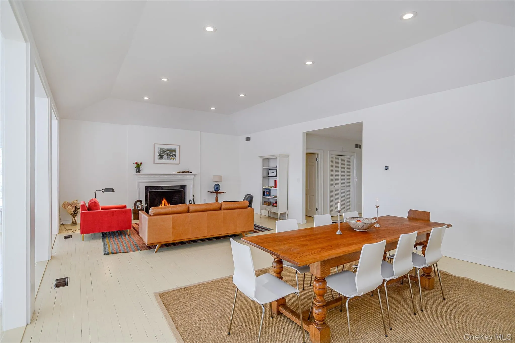 Dining area featuring a lit fireplace, recessed lighting, lofted ceiling, and light wood-style floors Dining area featuring a lit fireplace, recessed lighting, lofted ceiling, and light wood-style floors