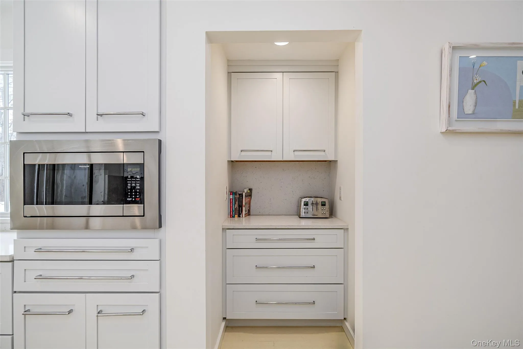 Kitchen view of stainless steel microwave, light stone counters, and white cabinetry Kitchen view of stainless steel microwave, light stone counters, and white cabinetry