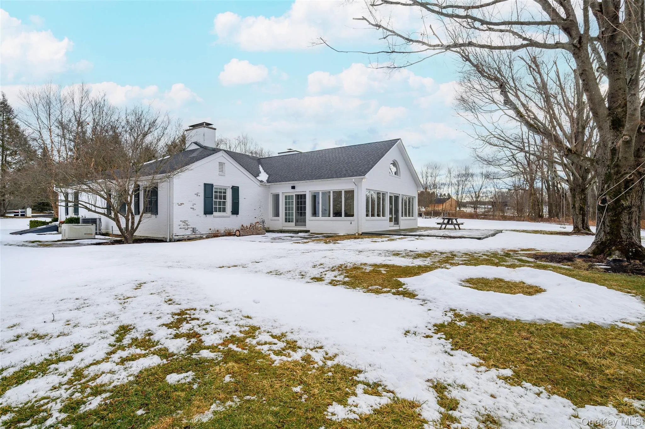 Snow covered property with a chimney and a sunroom Snow covered property with a chimney and a sunroom
