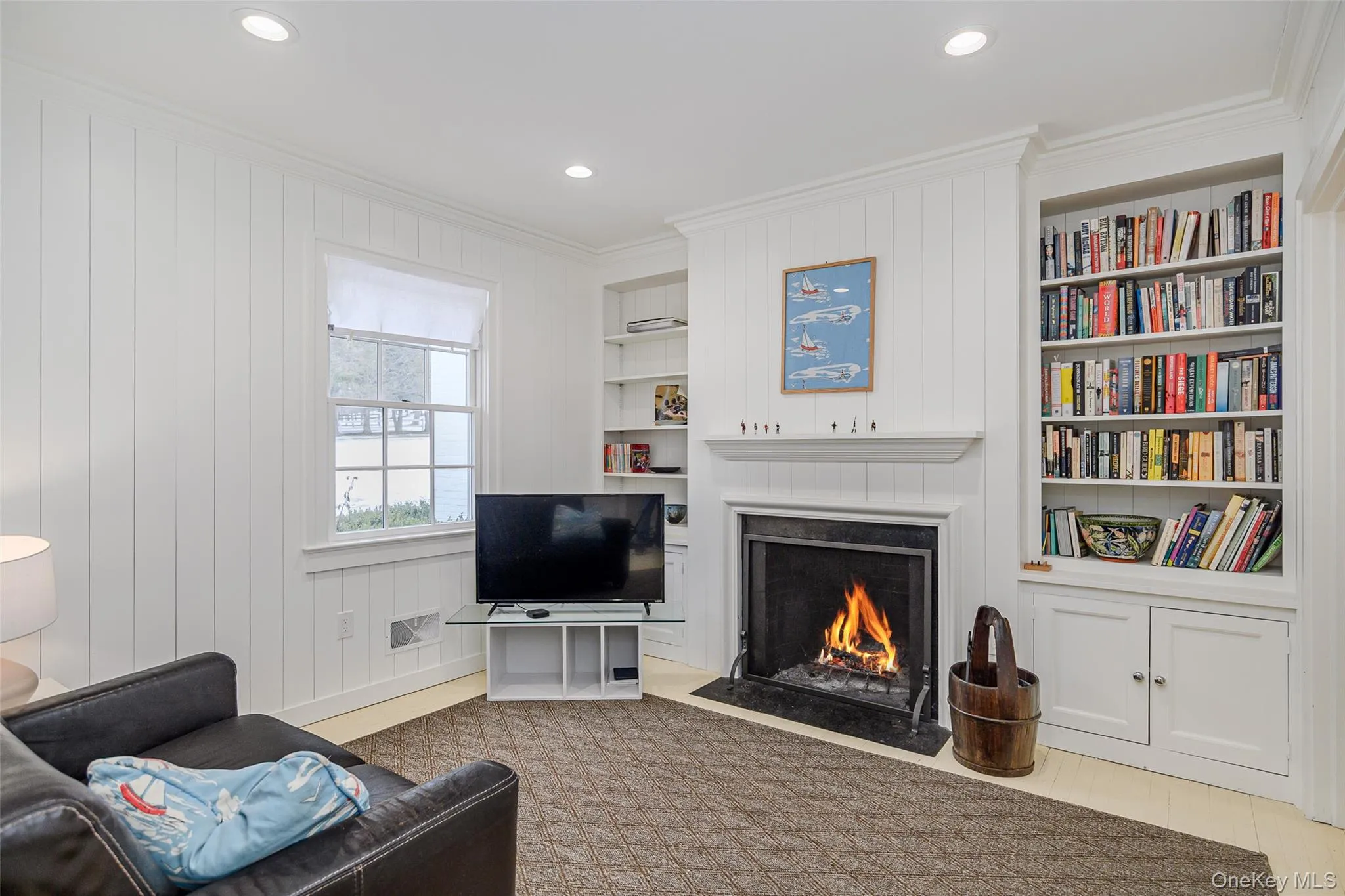 Living area with crown molding, a fireplace with flush hearth, recessed lighting, wood walls, and built in shelves Living area with crown molding, a fireplace with flush hearth, recessed lighting, wood walls, and built in shelves