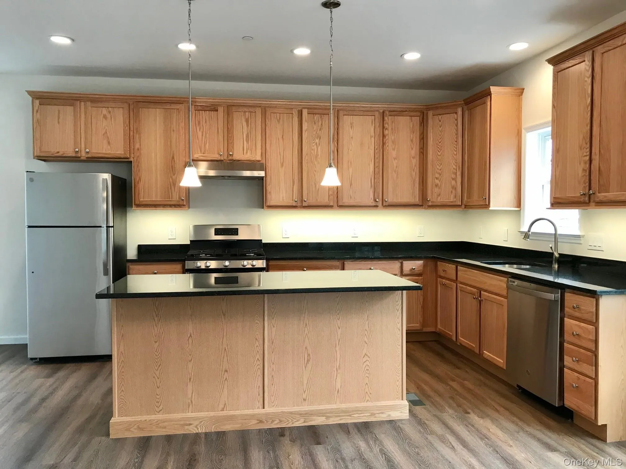 Kitchen with appliances with stainless steel finishes, pendant lighting, recessed lighting, a center island, and under cabinet range hood Kitchen with appliances with stainless steel finishes, pendant lighting, recessed lighting, a center island, and under cabinet range hood