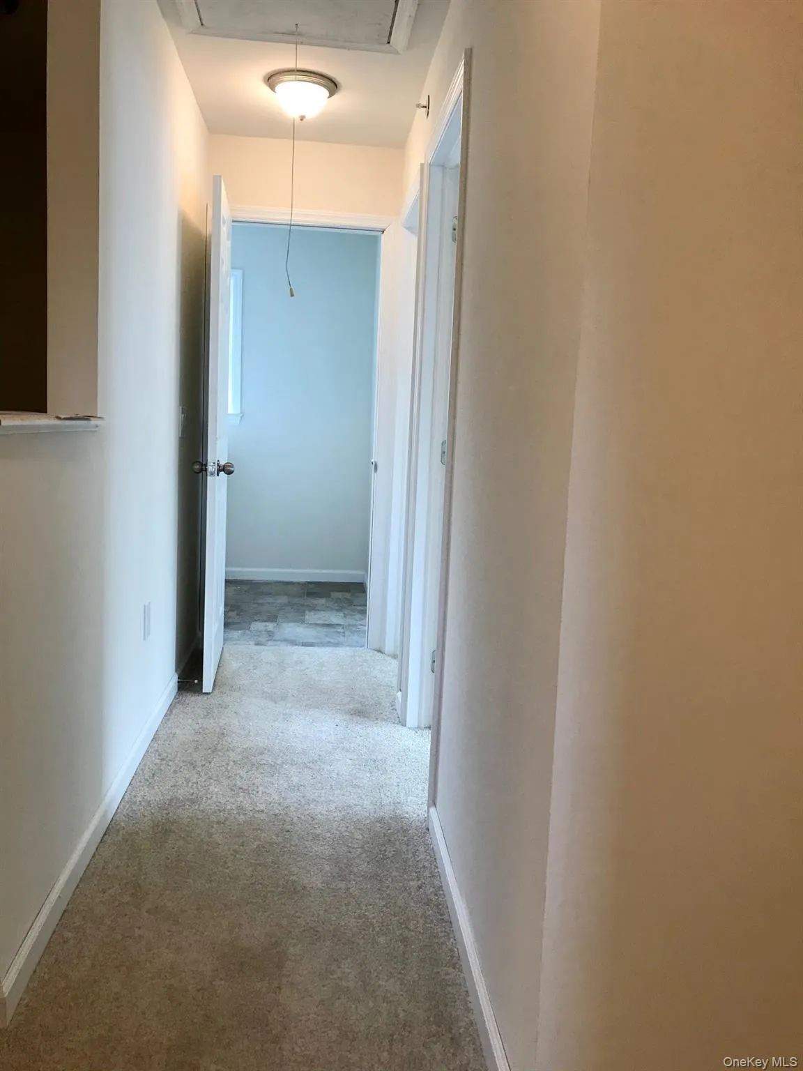 Corridor featuring attic access and light colored carpet Corridor featuring attic access and light colored carpet