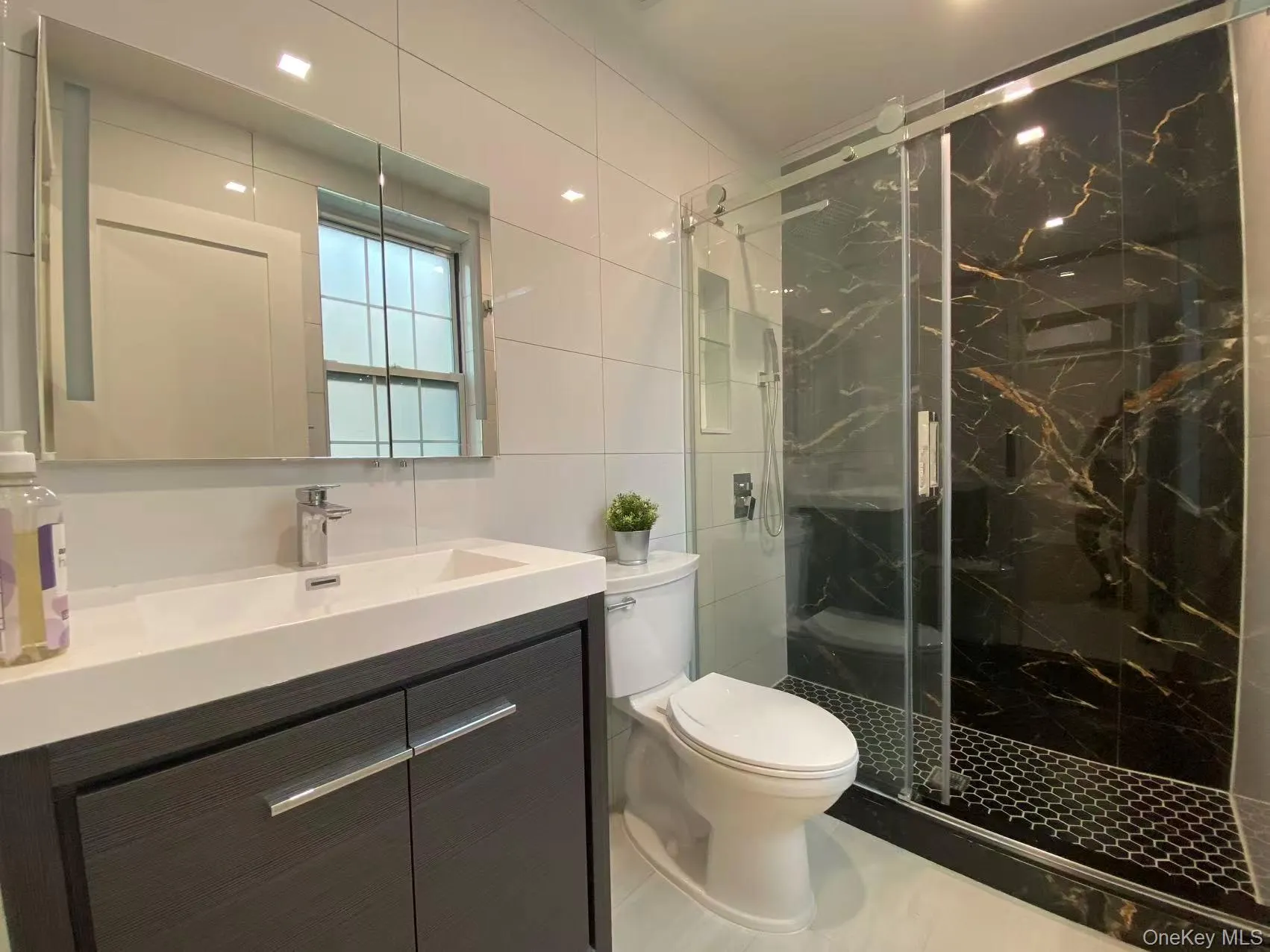 Bathroom with tile walls, vanity, and a marble finish shower Bathroom with tile walls, vanity, and a marble finish shower