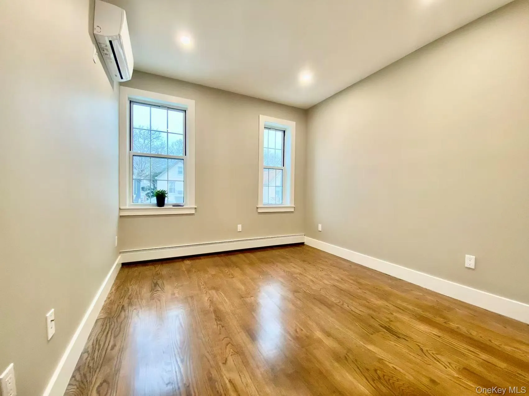 Unfurnished room featuring wood finished floors, a wall mounted air conditioner, a baseboard heating unit, and recessed lighting Unfurnished room featuring wood finished floors, a wall mounted air conditioner, a baseboard heating unit, and recessed lighting