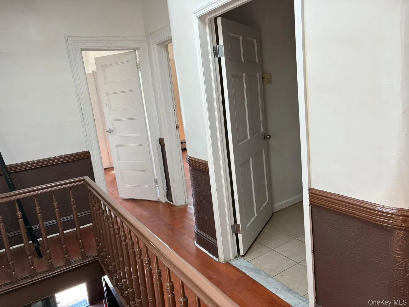 Hallway with light tile patterned floors, baseboard heating, and an upstairs landing Hallway with light tile patterned floors, baseboard heating, and an upstairs landing