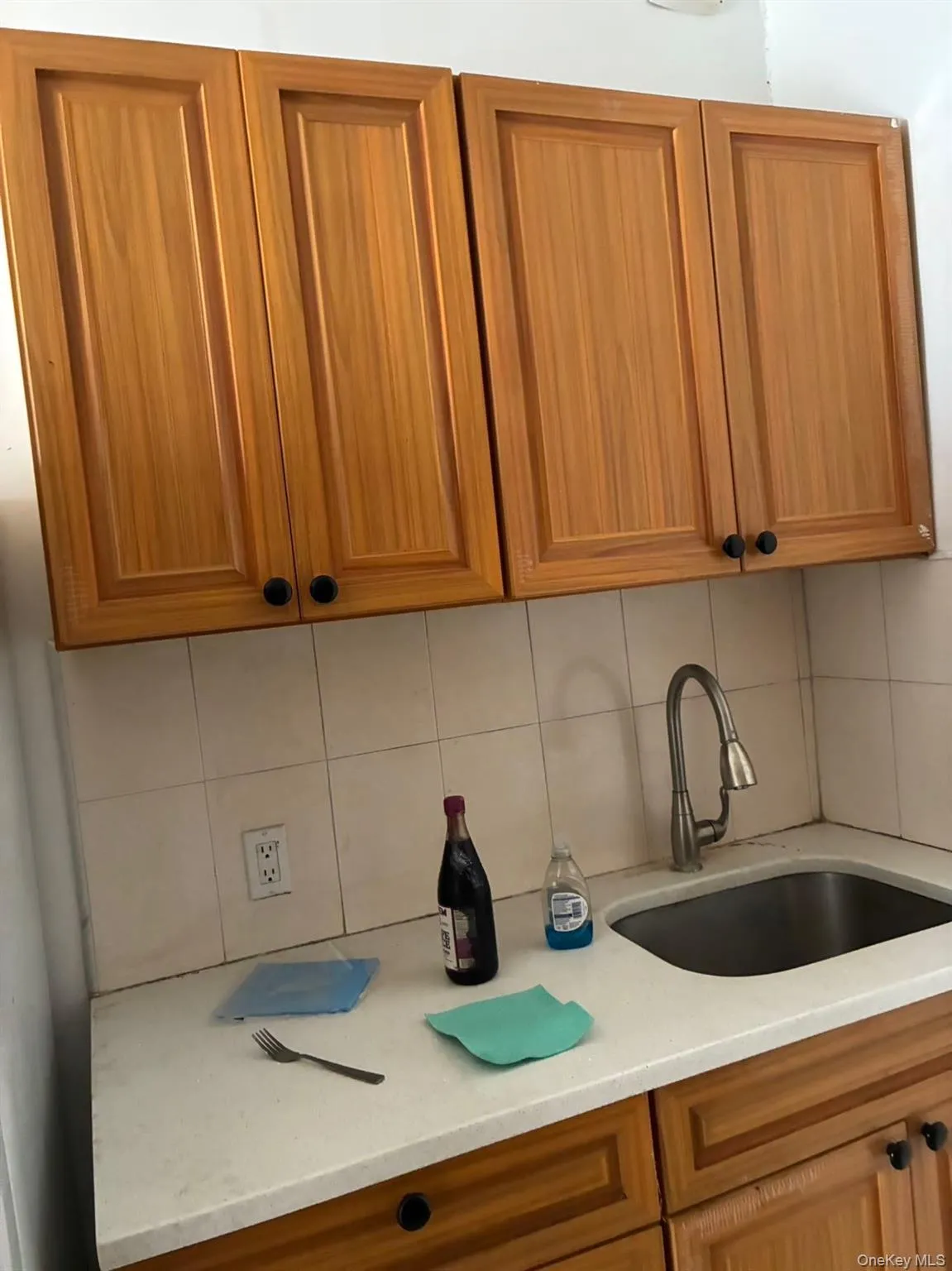 Kitchen featuring brown cabinetry, light stone countertops, and tasteful backsplash Kitchen featuring brown cabinetry, light stone countertops, and tasteful backsplash