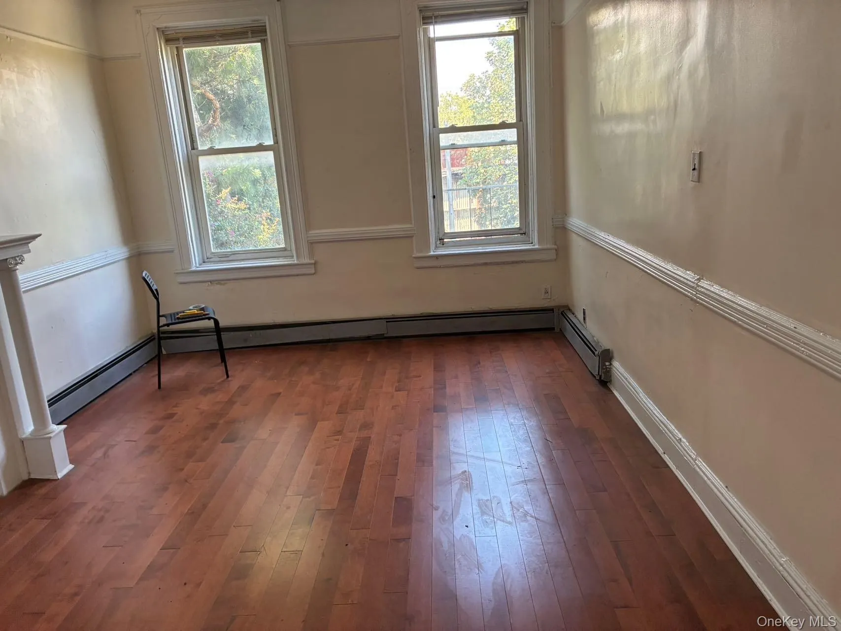 Empty room featuring dark wood finished floors and baseboard heating Empty room featuring dark wood finished floors and baseboard heating
