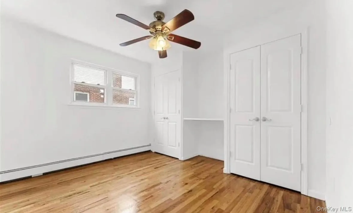 Unfurnished bedroom with two closets, a baseboard radiator, light wood finished floors, and ceiling fan Unfurnished bedroom with two closets, a baseboard radiator, light wood finished floors, and ceiling fan