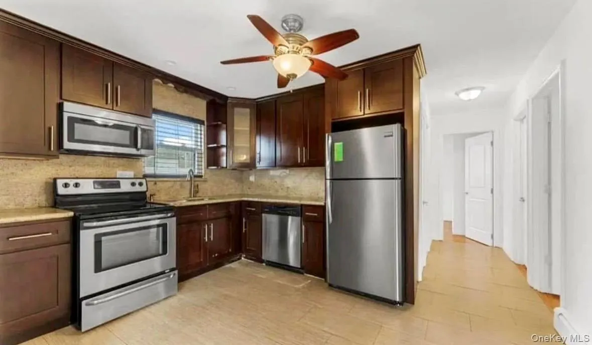 Kitchen with appliances with stainless steel finishes, dark brown cabinets, tasteful backsplash, and ceiling fan Kitchen with appliances with stainless steel finishes, dark brown cabinets, tasteful backsplash, and ceiling fan