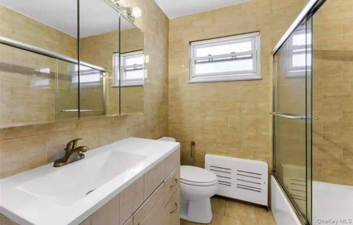 Full bath with vanity, enclosed tub / shower combo, and tile walls Full bath with vanity, enclosed tub / shower combo, and tile walls