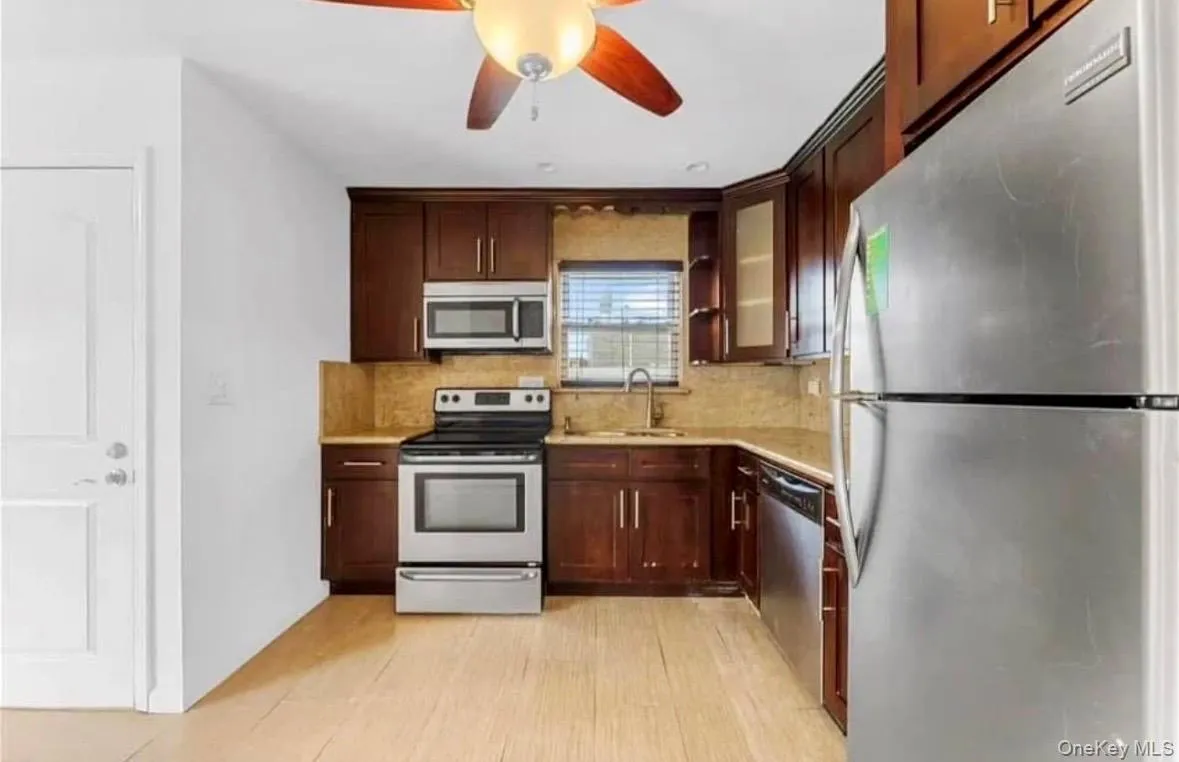 Kitchen featuring stainless steel appliances, glass insert cabinets, dark brown cabinets, and tasteful backsplash Kitchen featuring stainless steel appliances, glass insert cabinets, dark brown cabinets, and tasteful backsplash