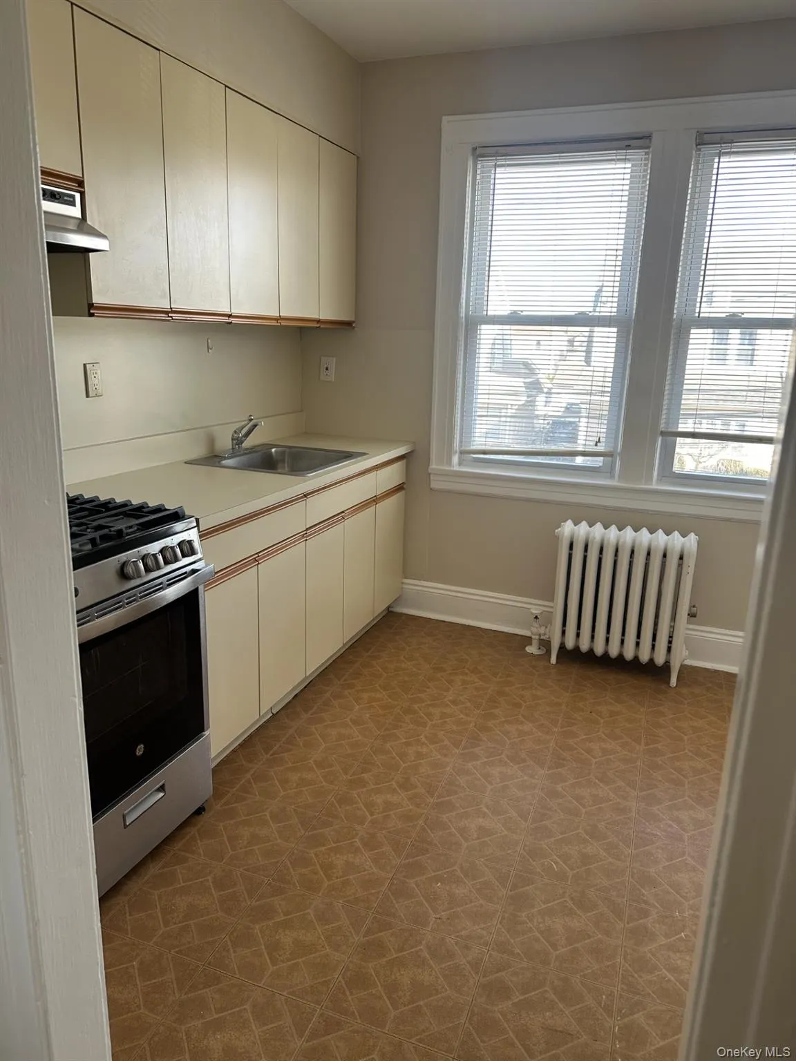 Kitchen featuring radiator heating unit, light countertops, stainless steel range with gas cooktop, and extractor fan Kitchen featuring radiator heating unit, light countertops, stainless steel range with gas cooktop, and extractor fan